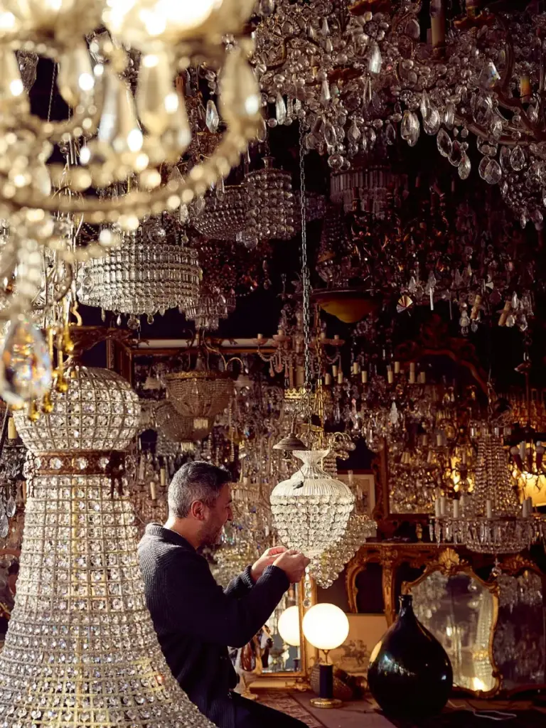 Erkan Tahta zwischen antiken Kristallkronleuchtern in der Kronleuchter-Galerie von Light Delux in Berlin-Kreuzberg