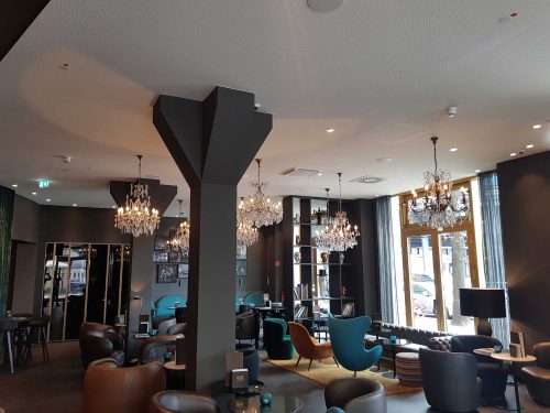 Lobby des Motel One Berlin-Ku’Damm mit Kristall Kronleuchtern über der Sitzlandschaft